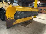 une grande déneigeuse jaune garée dans un entrepôt