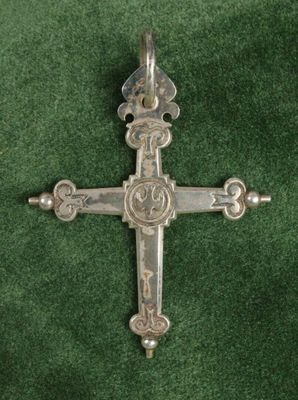 une croix en argent sur un fond de velours vert orné d'un motif décoratif