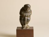 une petite statue représentant un homme en combinaison spatiale, posée sur un socle en bois