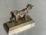 une statue en bronze représentant un taureau, posée sur un socle en métal