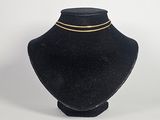 mannequin en velours noir portant un collier à chaîne dorée, sur fond blanc