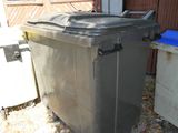 deux poubelles devant un immeuble, avec un garage en arrière-plan