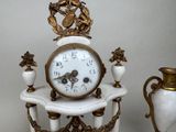 a clock sitting on top of a table next to two vases