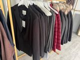 clothes hanging on a rack in a clothing store next to a window