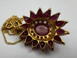 gold plated necklace with a pink stone center surrounded by a gold chain