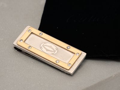 a silver and gold money clip sitting on top of a black bag