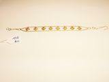a close up of a gold bracelet on a white surface