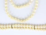 trois colliers de perles et un bracelet posés sur un fond blanc