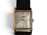 une vieille montre avec un bracelet en cuir noir posée sur un fond blanc