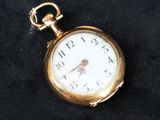 une petite montre de poche en or posée sur un tissu noir