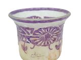 un vase violet et blanc orné de fleurs, posé sur une surface blanche