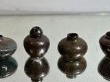 four vases sitting on a glass table with a white background