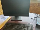 un écran d'ordinateur et un clavier posés sur un bureau devant une fenêtre
