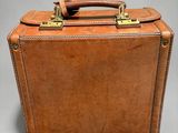 a brown suitcase with a handle on a gray background