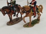 two figurines of men riding horses with flags