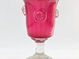 un vase en verre rose muni d'une anse, posé sur un socle