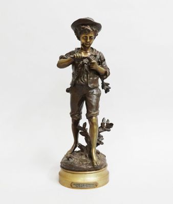 a bronze statue of a boy with a bird on his shoulder