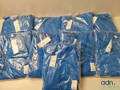 plusieurs sacs remplis de chemises bleues posés sur une table blanche