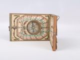 an old book with a compass on it sitting on top of a white surface