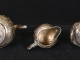 three antique silver teapots on a black background