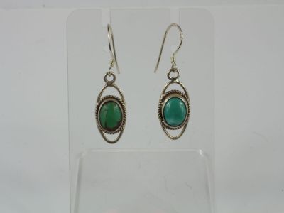 a pair of earrings with a green stone in the middle