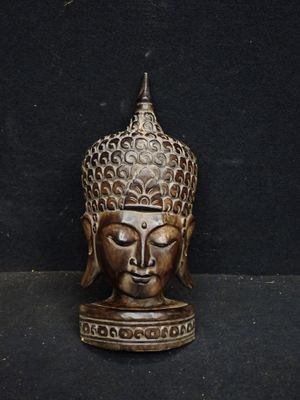 une image représentant une statue en bronze représentant une tête de Bouddha sur fond noir