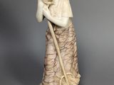 statue d'une femme tenant une serpillière à la main et portant un chapeau sur la tête