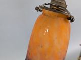 an orange and blue vase sitting on a table next to a silver spoon