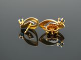 two gold earrings with blue stones on a reflective surface