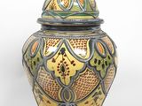 un vase jaune et vert muni d'un couvercle, sur fond blanc