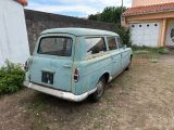 an old blue car parked in front of a house
