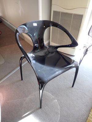 une chaise en plastique noire posée dans un coin d'une pièce