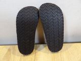 the soles of a pair of black slippers on a wooden floor