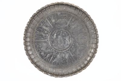 une plaque d'argent ornée d'un motif sur une surface blanche