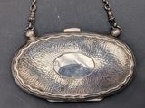 an antique silver purse on a chain with a picture in the center