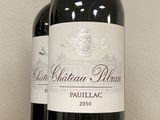 three bottles of red wine sitting on top of a wooden block