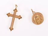 two gold crosses and a coin on a white surface