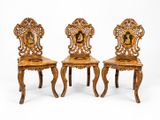 trois chaises en bois ornées de sculptures, disposées les unes à côté des autres