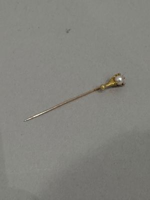 a gold pin with a pearl on it on a table