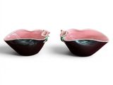 two pink and black bowls sitting on top of a white surface