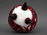 a red and white glass ball with black spikes on it