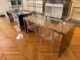 une table de salle à manger en verre avec des chaises transparentes et une cheminée en arrière-plan