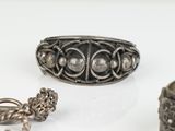 two silver rings and a bracelet are sitting on a white surface