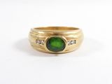 gros plan d'une bague en or avec une pierre verte