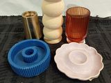 four different colored vases and a candle holder on a table