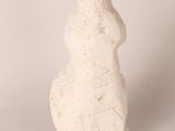 statue of a man with a hat on his head, sitting on a white surface