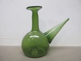 un vase en verre vert avec un couvercle noir posé par terre