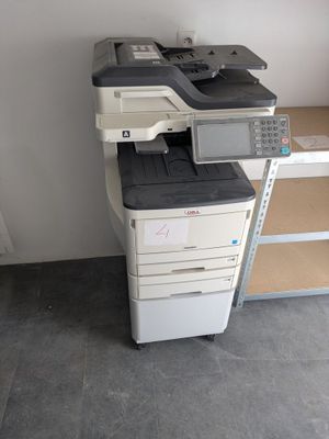 a printer sitting on top of a desk next to a shelf