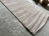 un tapis posé à même le sol dans un entrepôt, avec des cartons à perte de vue en arrière-plan