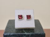 a pair of red stone stud earrings sitting on top of a marble block
